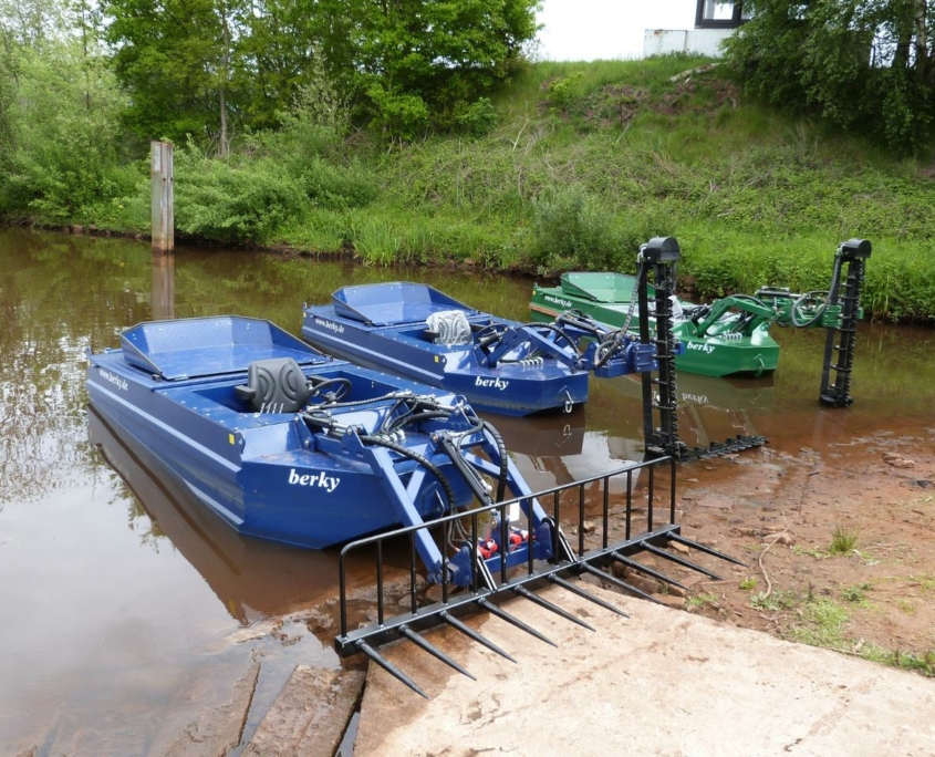 2 blaue und ein grünes Mähboote im Wasser